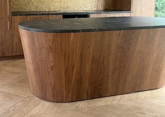 Curved walnut island under a black stone top