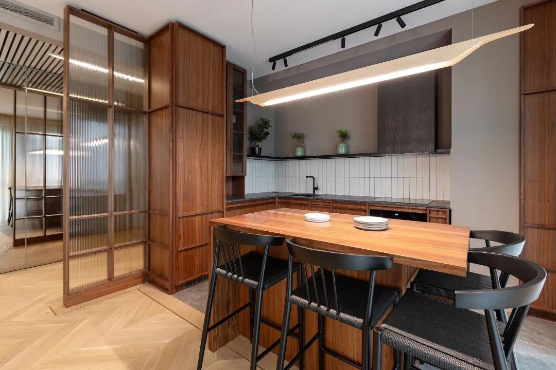 Japandi kitchen in walnut with ribbed glass doors, a timber bar table and a sculpted pendant light