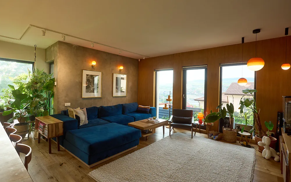 The living room with a large deep blue sofa, a low wooden coffee table and tall windows