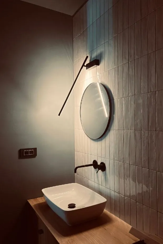 Vessel basin on an oak top below a round mirror and a slim wall light