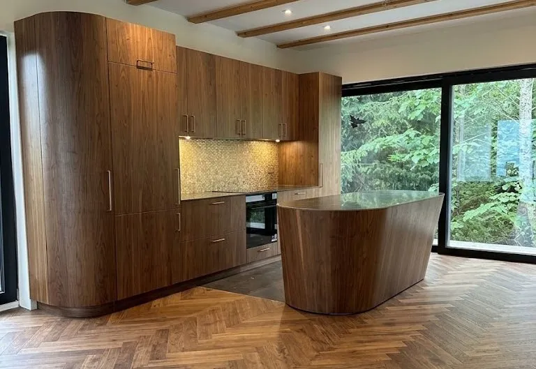 Walnut kitchen with floor to ceiling cabinets, a rounded island and garden glazing